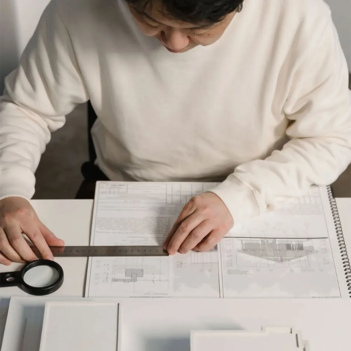 Arquitecto trabajando con planos y maqueta en mesa de diseño, proceso creativo técnico