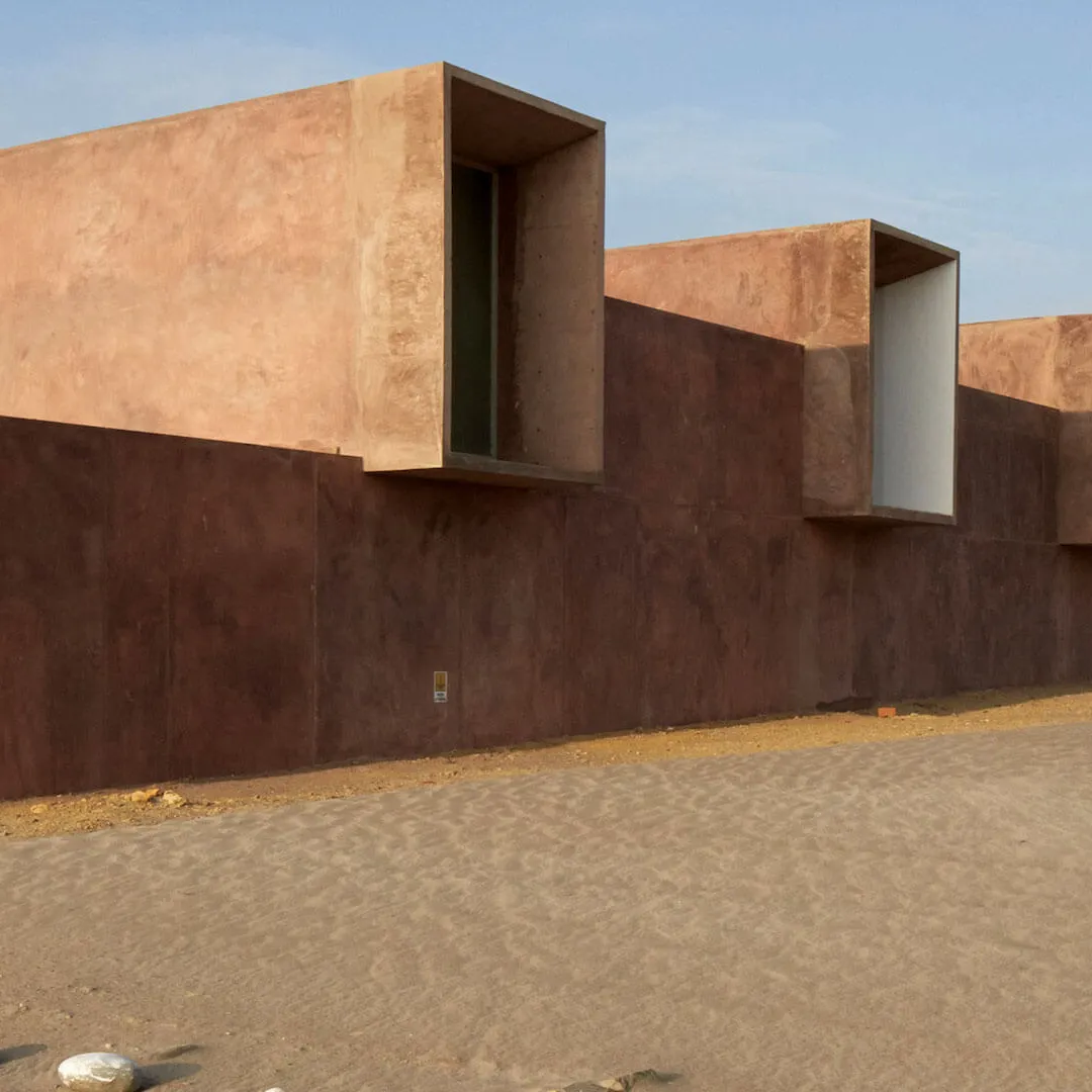 Edificio de arquitectura moderna en el desierto con paredes rojas y grandes ventanales