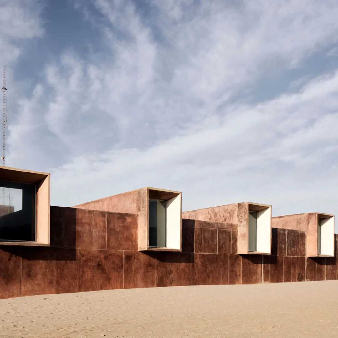 Edificio moderno en el desierto con estructuras en forma de cubo y pared roja